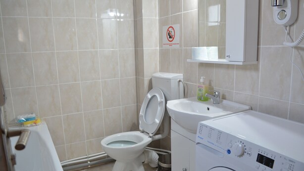 A bathroom with a toilet, sink, and washing machine. - Alexys Residence 7 (Iasi)