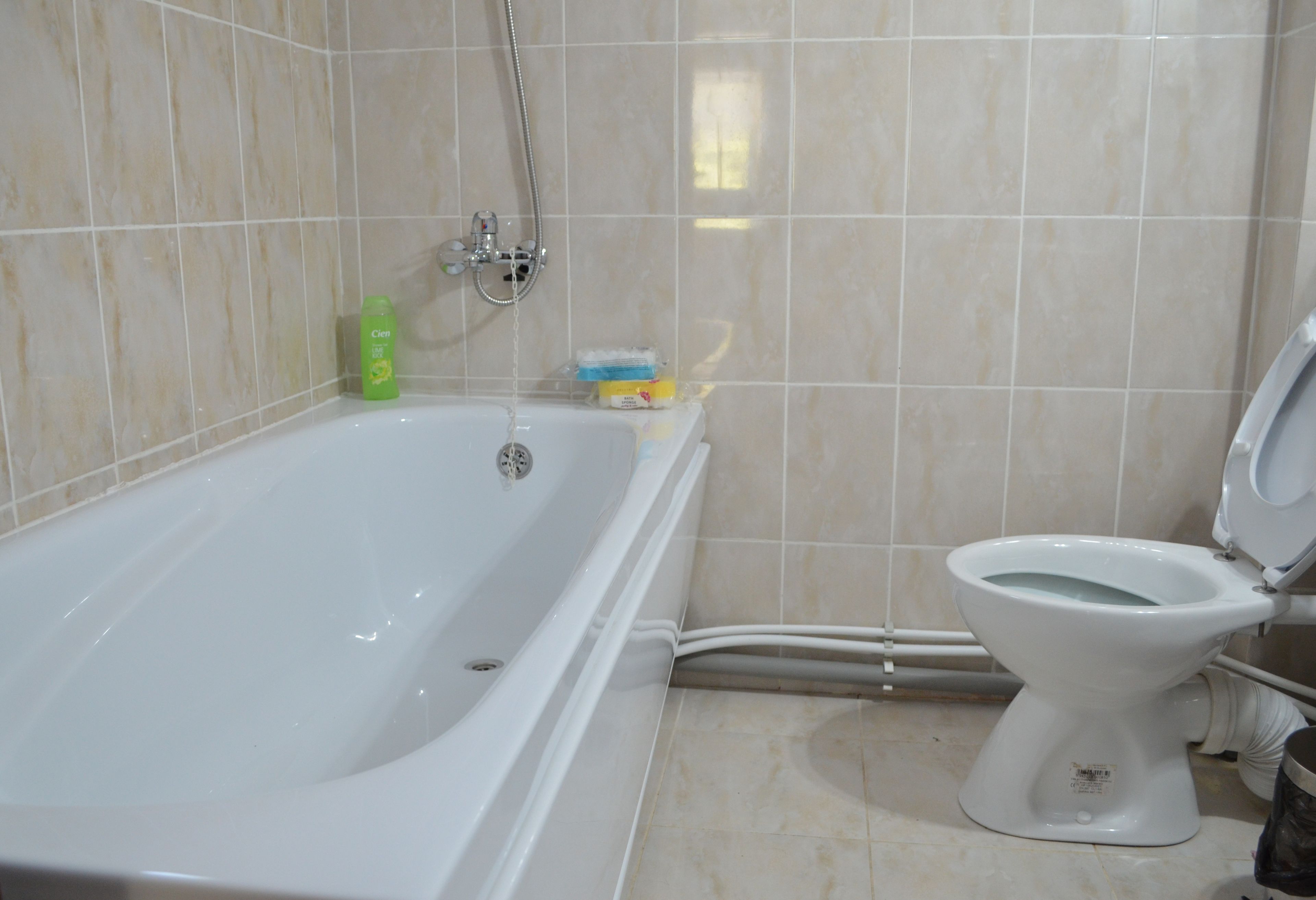 Et badeværelse med badekar, toilet og brusearmatur.
