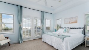 Une chambre à coucher avec un lit, des rideaux, une chaise et un tableau accroché au mur.