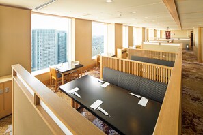 A modern hotel room with a large window offering a city view, a seating area with a sofa and a table, and a carpeted floor. - Shinagawa Prince Hotel East Tower (Tokyo)