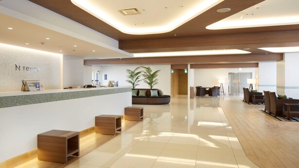 A modern hotel lobby with a reception desk, seating area, and a large potted plant. - Shinagawa Prince Hotel N Tower (Tokyo)
