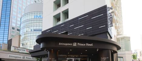 L’entrée de l’hôtel Shingawa Prince, avec son design moderne, sa façade en verre et les panneaux indiquant l’Aqua Park et le cinéma IMAX en arrière-plan.