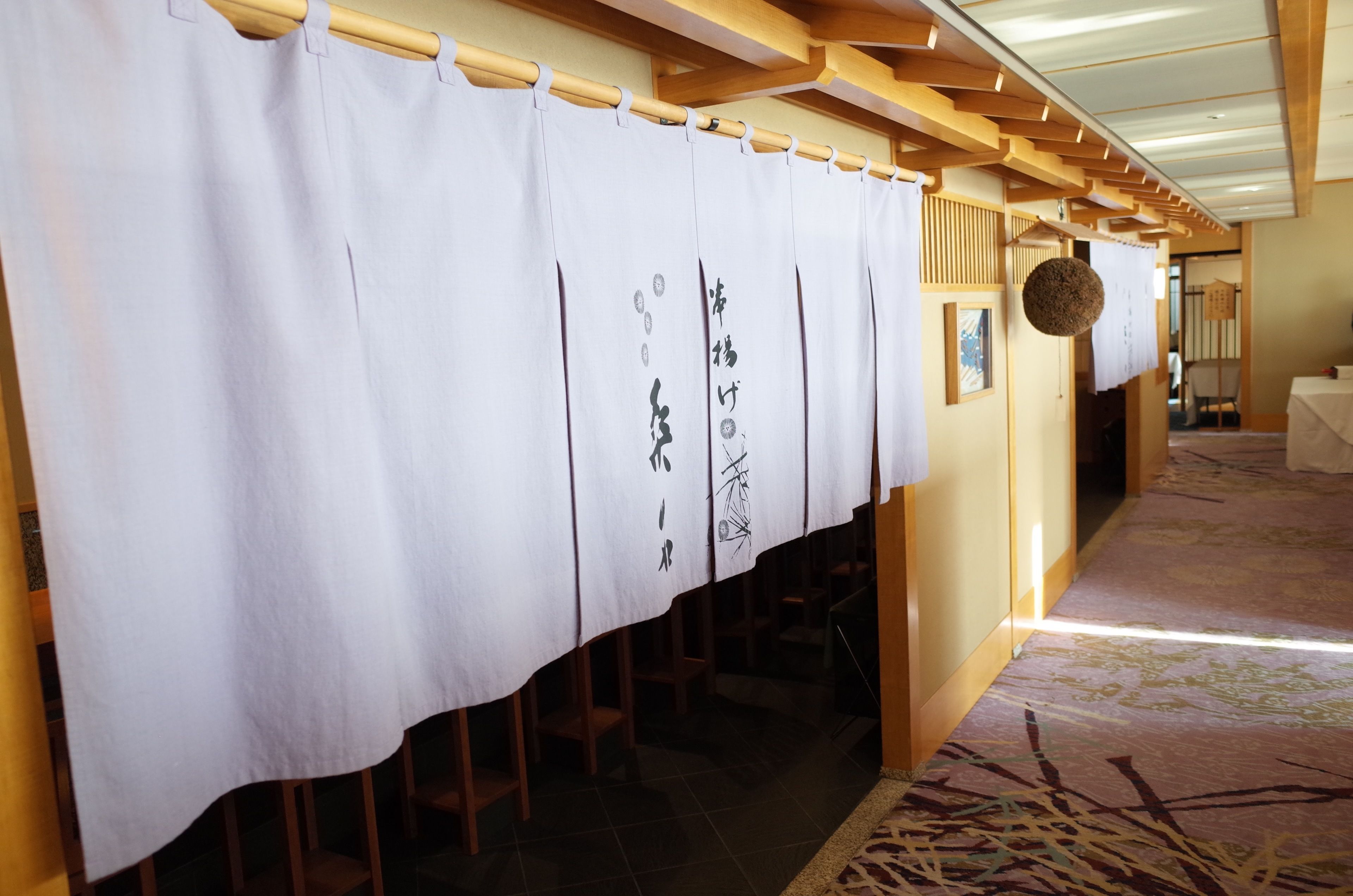 Une pièce de style japonais traditionnel, avec un sol recouvert de tatamis, un paravent en papier de riz (shoji) et un plafond en poutres apparentes.