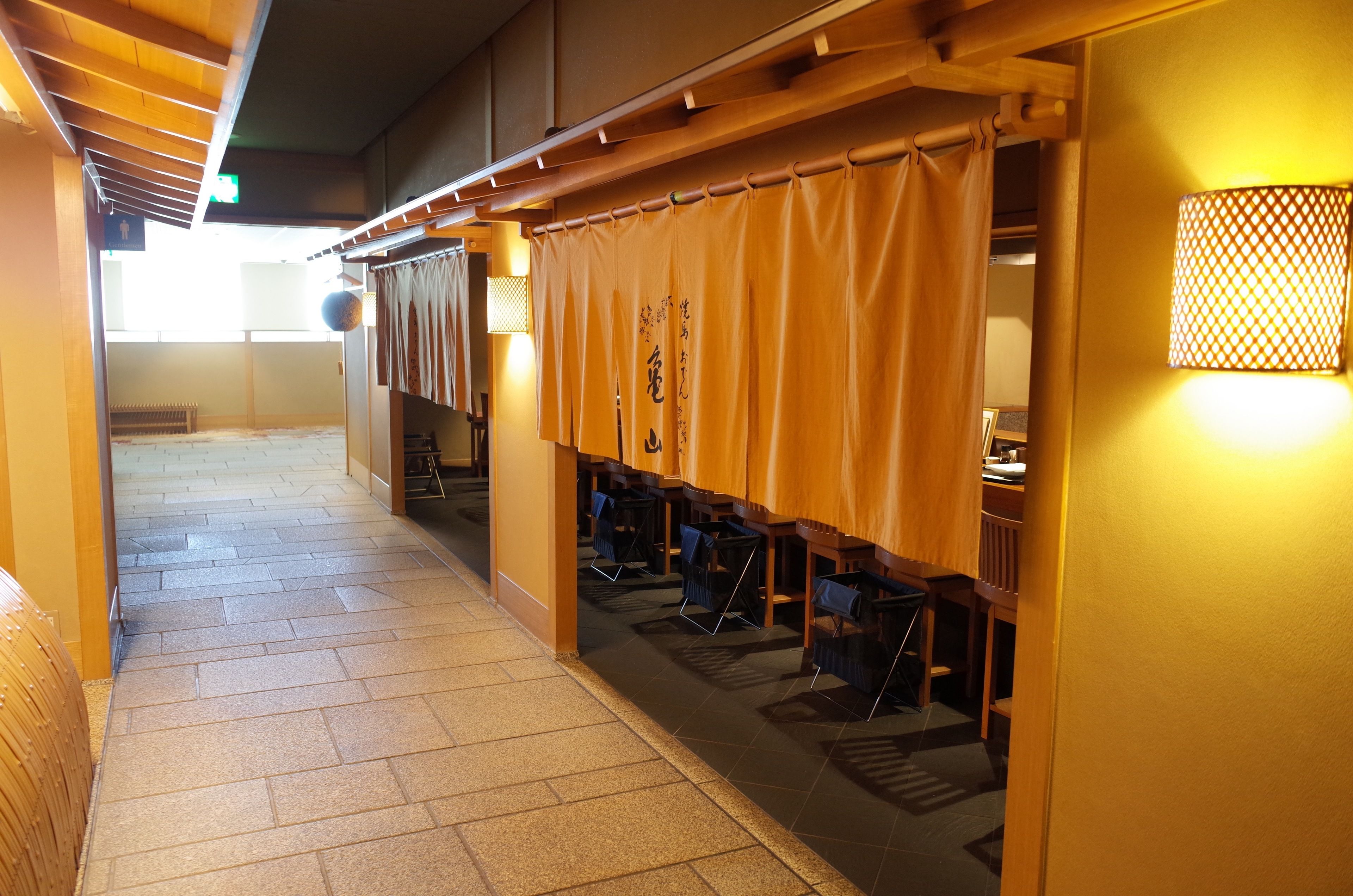 Un pasillo con esteras de tatami, muebles de madera y decoración japonesa tradicional.
