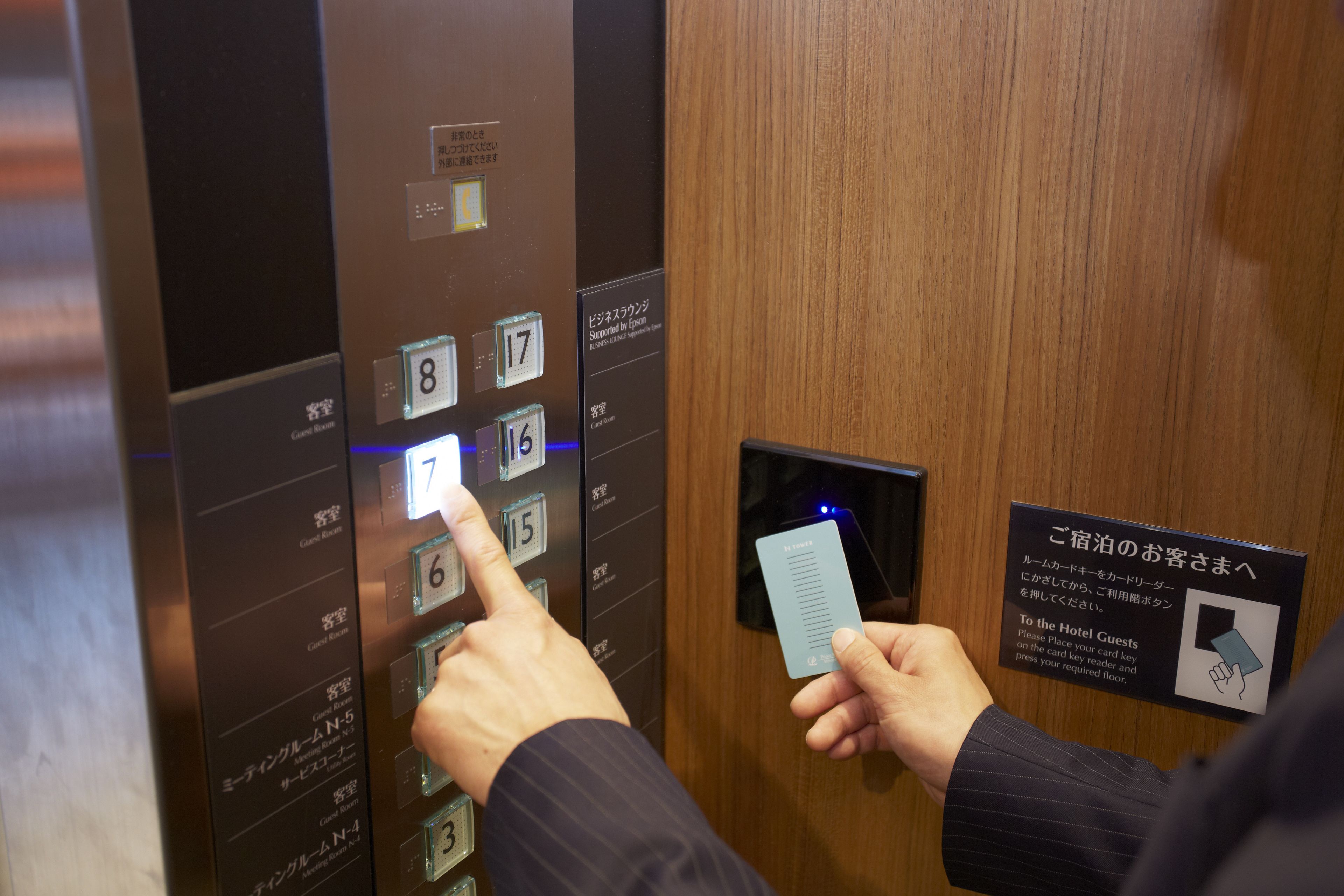 Una persona utilizando un panel de control de ascensor con botones numerados y un lector de tarjetas.