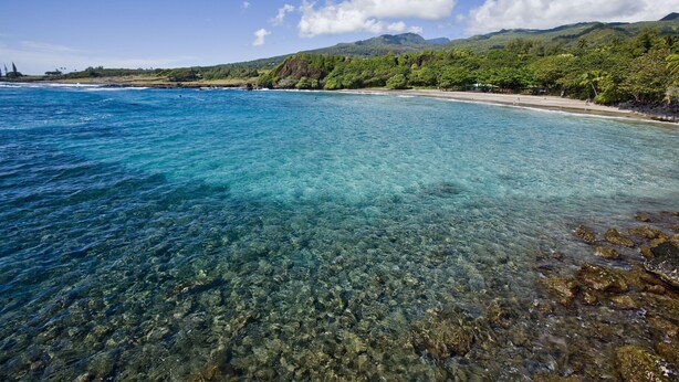 A clear coastal view with a sandy beach and rocky shoreline.