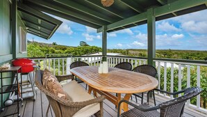 A covered outdoor patio with a wooden table, wicker chairs, and a ceiling fan.