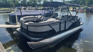 Un bateau ponton était amarré dans une marina, avec un espace de repos abrité et un auvent.
