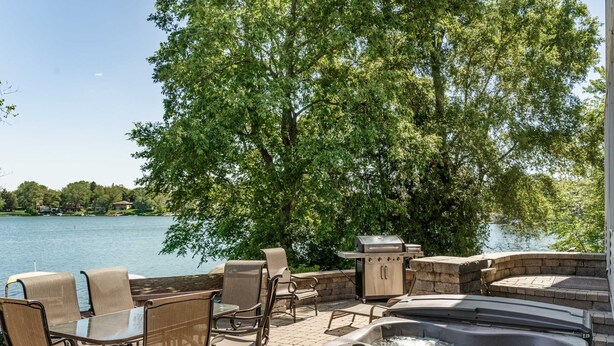 Une terrasse extérieure avec un jacuzzi, un coin salon et un barbecue.