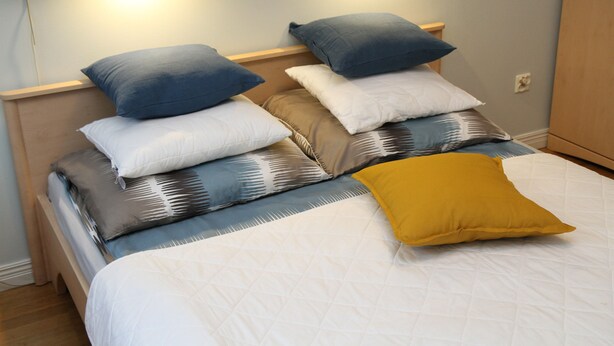 A neatly made bed with multiple pillows and a single blanket. - 270 Pulawska (Warsaw)