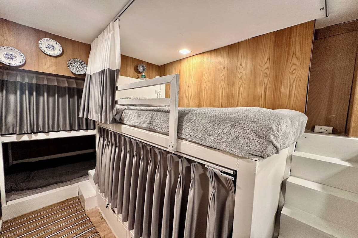 A bunk bed with a headboard, a small table, and a wall-mounted shelf.