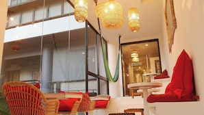 Un intérieur moderne avec des meubles en osier, des coussins rouges et des lampes en osier suspendues.