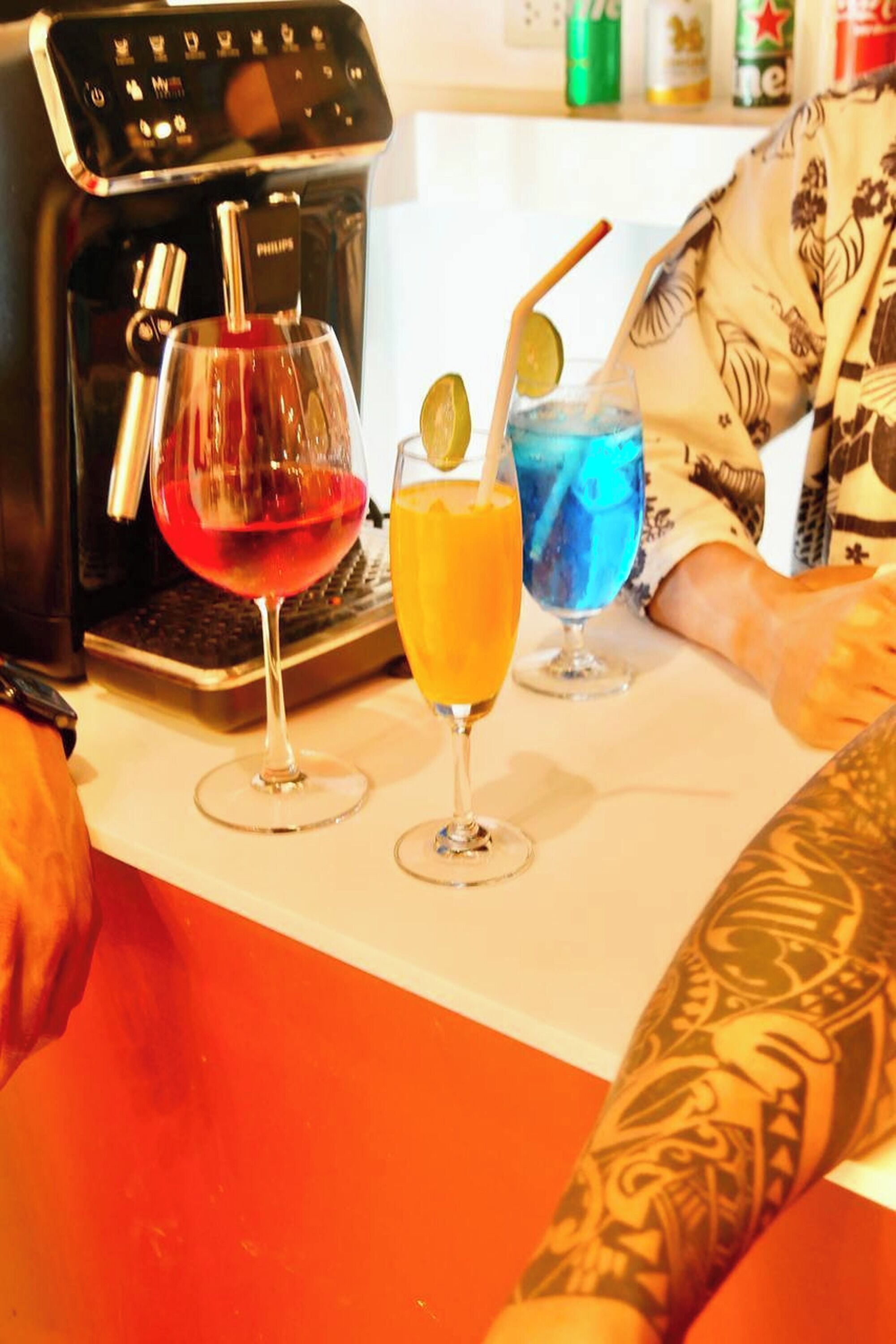 A bar area with a coffee machine, a laptop, and three drinks on the counter.