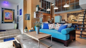 Un intérieur moderne avec un canapé bleu, des étagères en bois et une grande fenêtre.