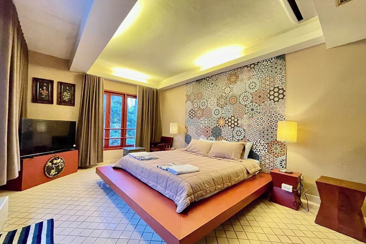 A modern bedroom with a large bed, a flat-screen TV, and a patterned wall.