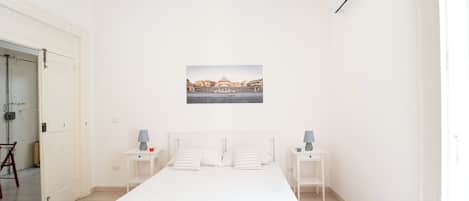 A minimalist bedroom with a single bed, two bedside tables, and a wall-mounted picture.
