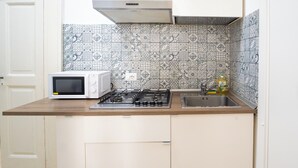 A kitchen with a microwave, gas stove, and a sink. - Monteoliveto Modern Flat by Wonderful Italy (Naples)