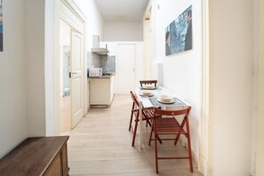 Un couloir étroit mène à une cuisine et à un coin repas où une table est dressée pour deux personnes.