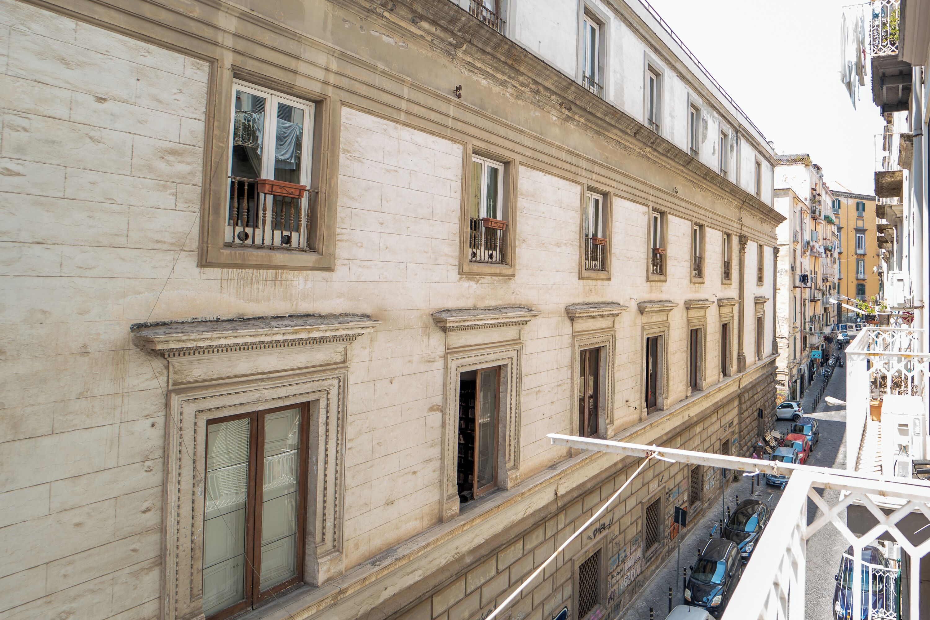 A multi-story building with classical architecture, featuring ornate window frames and a balcony with a wrought iron railing.