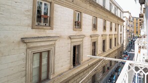 A multi-story building with classical architecture, featuring ornate window frames and a balcony with a wrought iron railing. - Monteoliveto Modern Flat by Wonderful Italy (Naples)