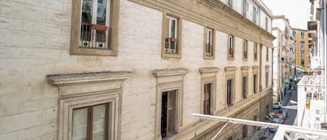 Un edificio de varios pisos con arquitectura clásica, que presenta marcos de ventanas ornamentados y un balcón con barandilla de hierro forjado.