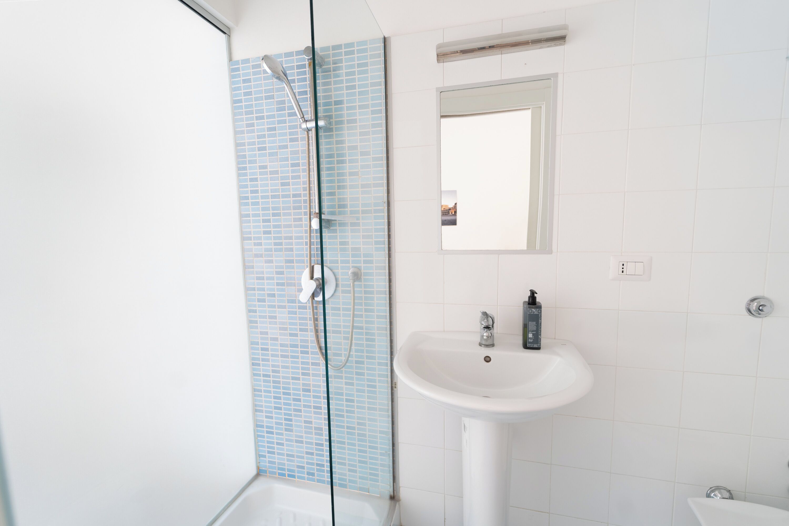 Une salle de bain avec une douche, un lavabo et un miroir.