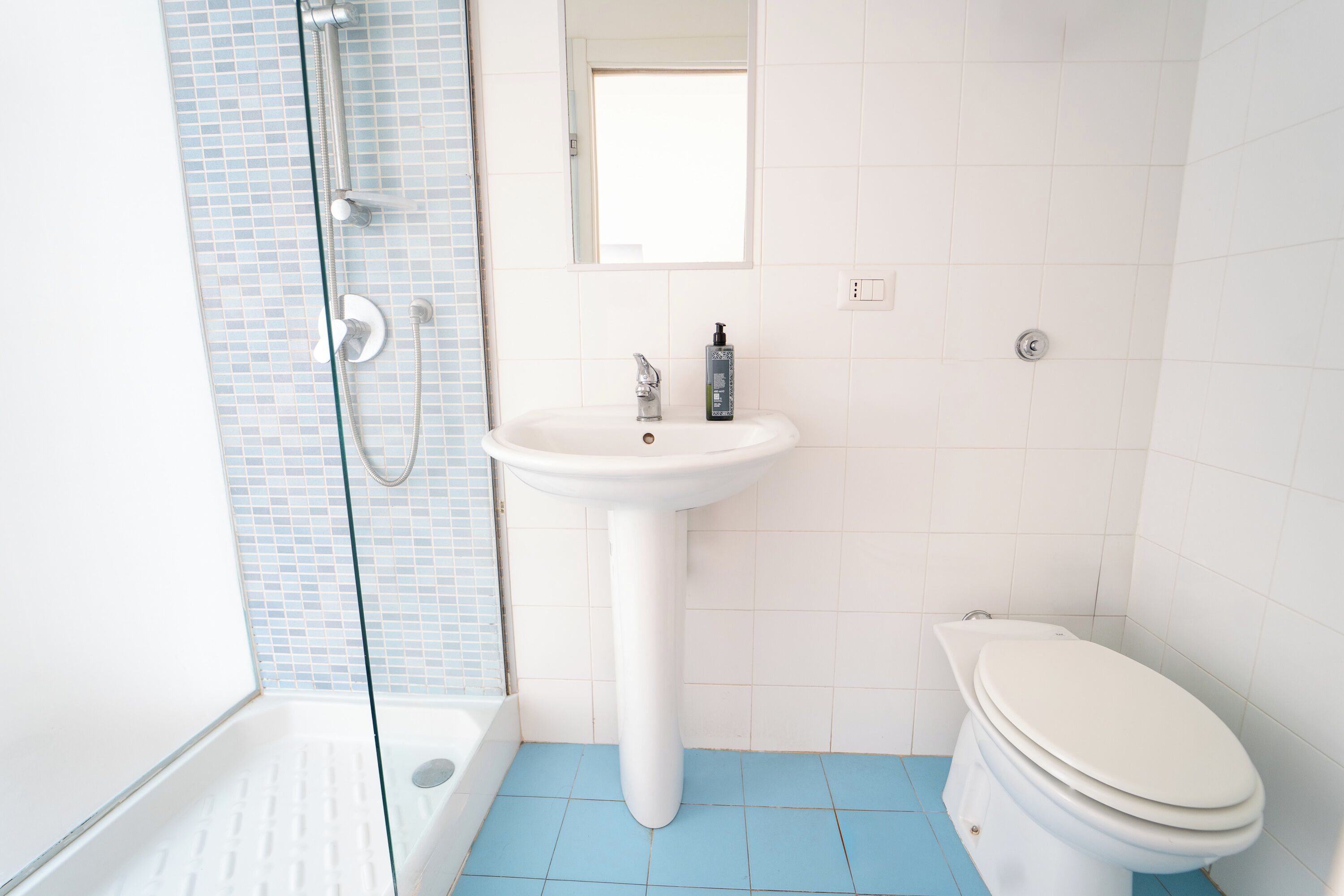 A bathroom with a white sink, a toilet, and a glass shower enclosure.