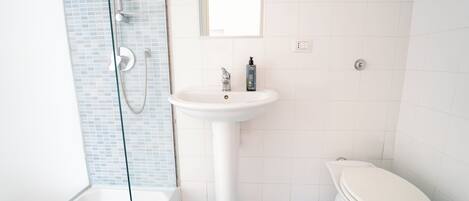 A bathroom with a white sink, a toilet, and a glass shower enclosure.