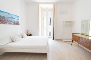 Une chambre à coucher avec un lit, une commode, un miroir et un tableau accroché au mur.