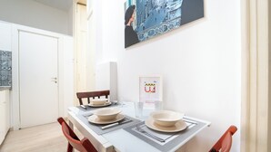 A dining area with a table set for two, two chairs, a framed welcome sign, and a wall-mounted picture. - Monteoliveto Modern Flat by Wonderful Italy (Naples)