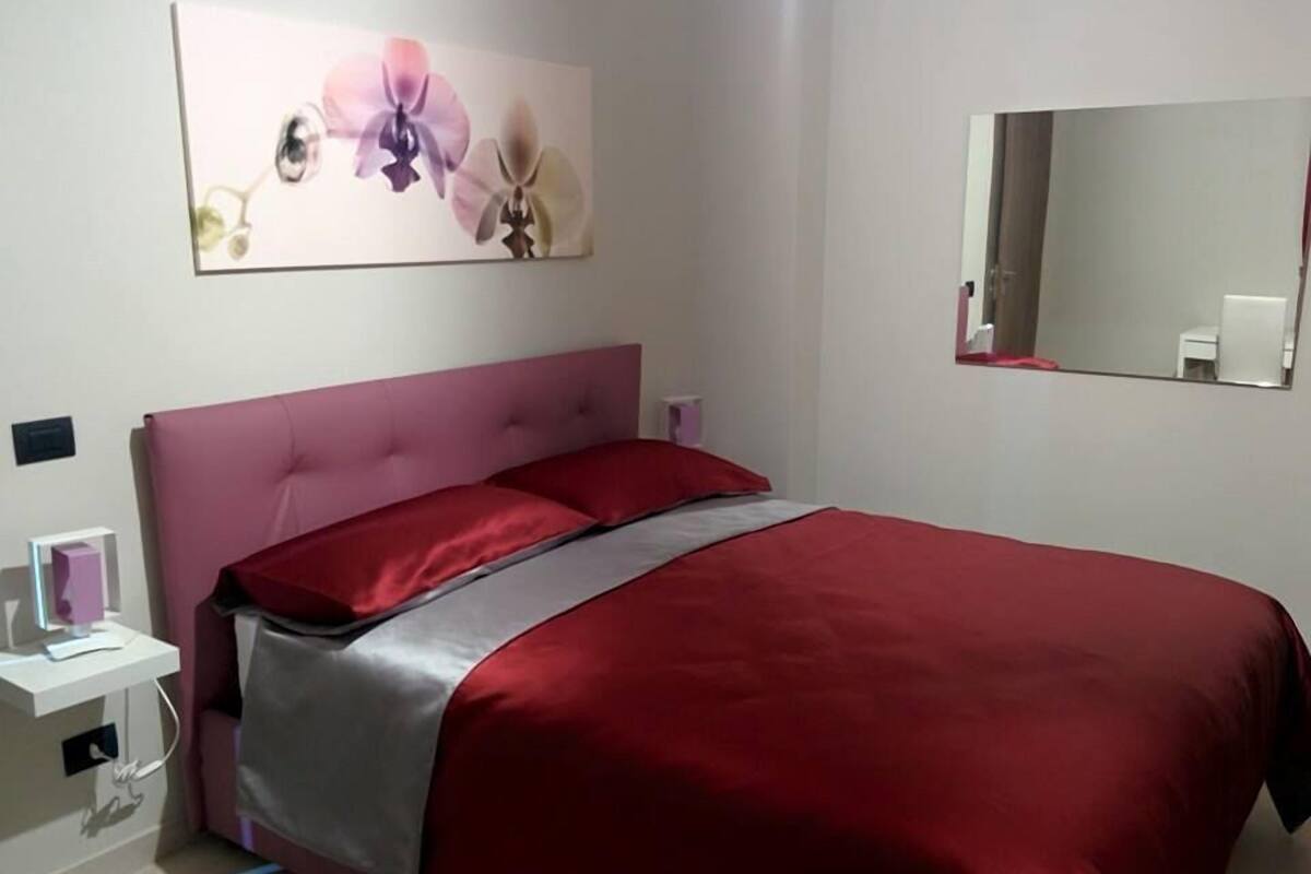 Ein Schlafzimmer mit einem rosa Bettgestell, einer roten Tagesdecke und einem großen Blumenbild über dem Bett.