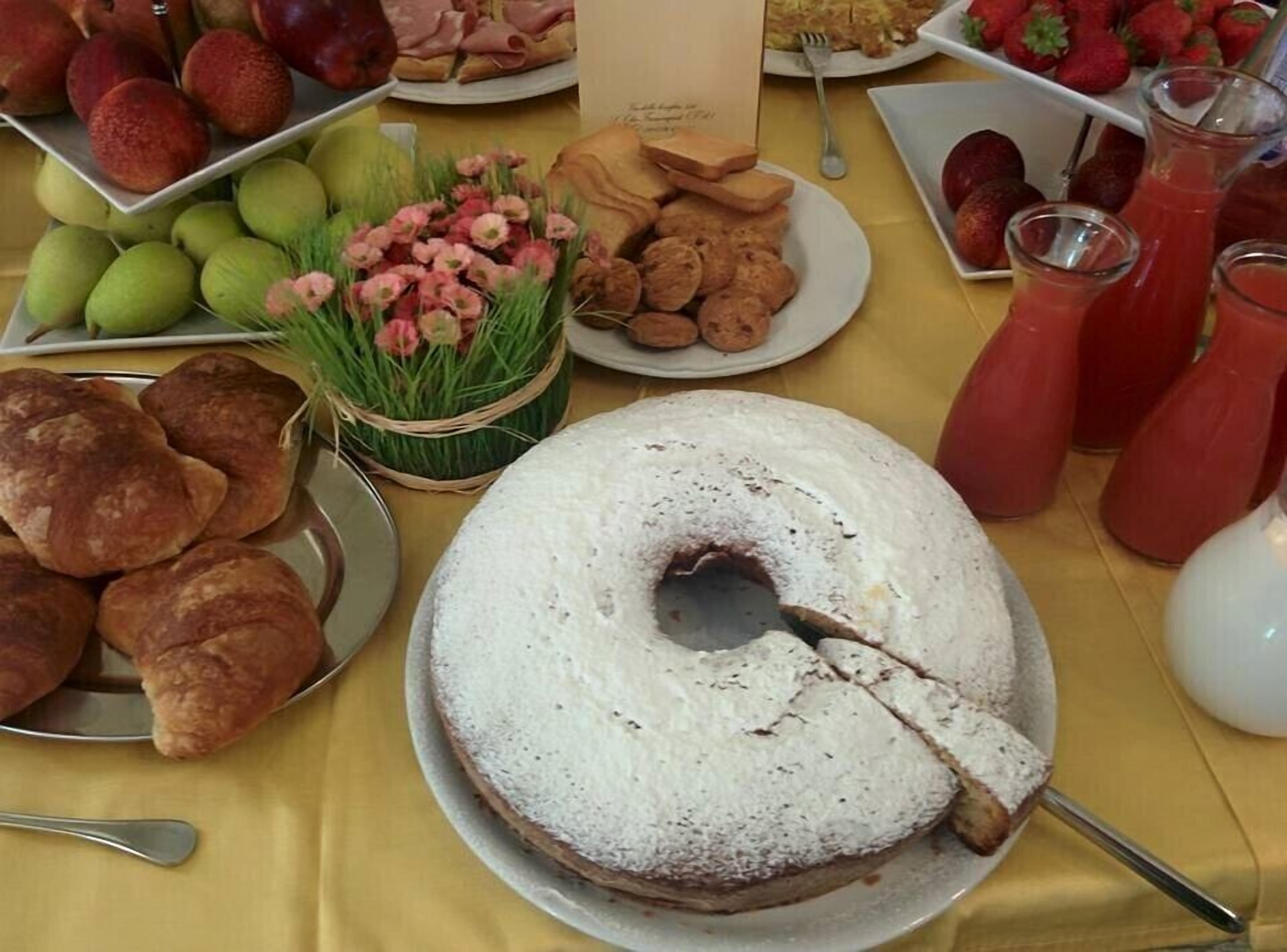 Pöydällä on erilaisia ruoka-aineita, kuten kakku, hedelmiä ja juomia.