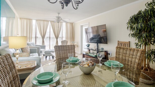 Un coin repas avec une table ronde, des chaises et un téléviseur en arrière-plan.