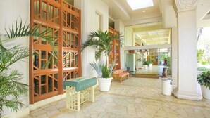 A spacious lobby with a directory table, potted plants, and a view into a restaurant area.