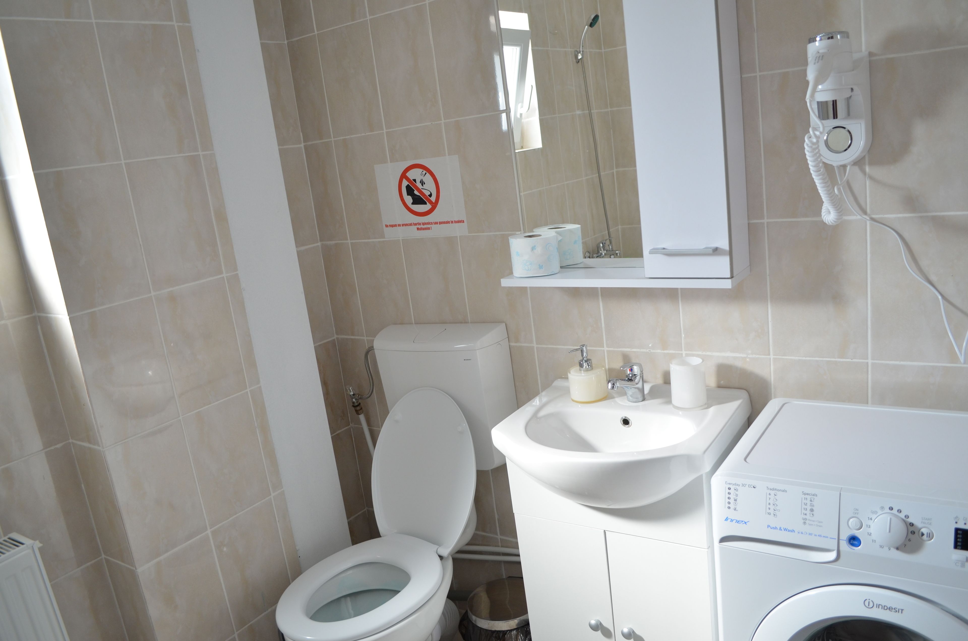 A bathroom with a toilet, sink, and washing machine.