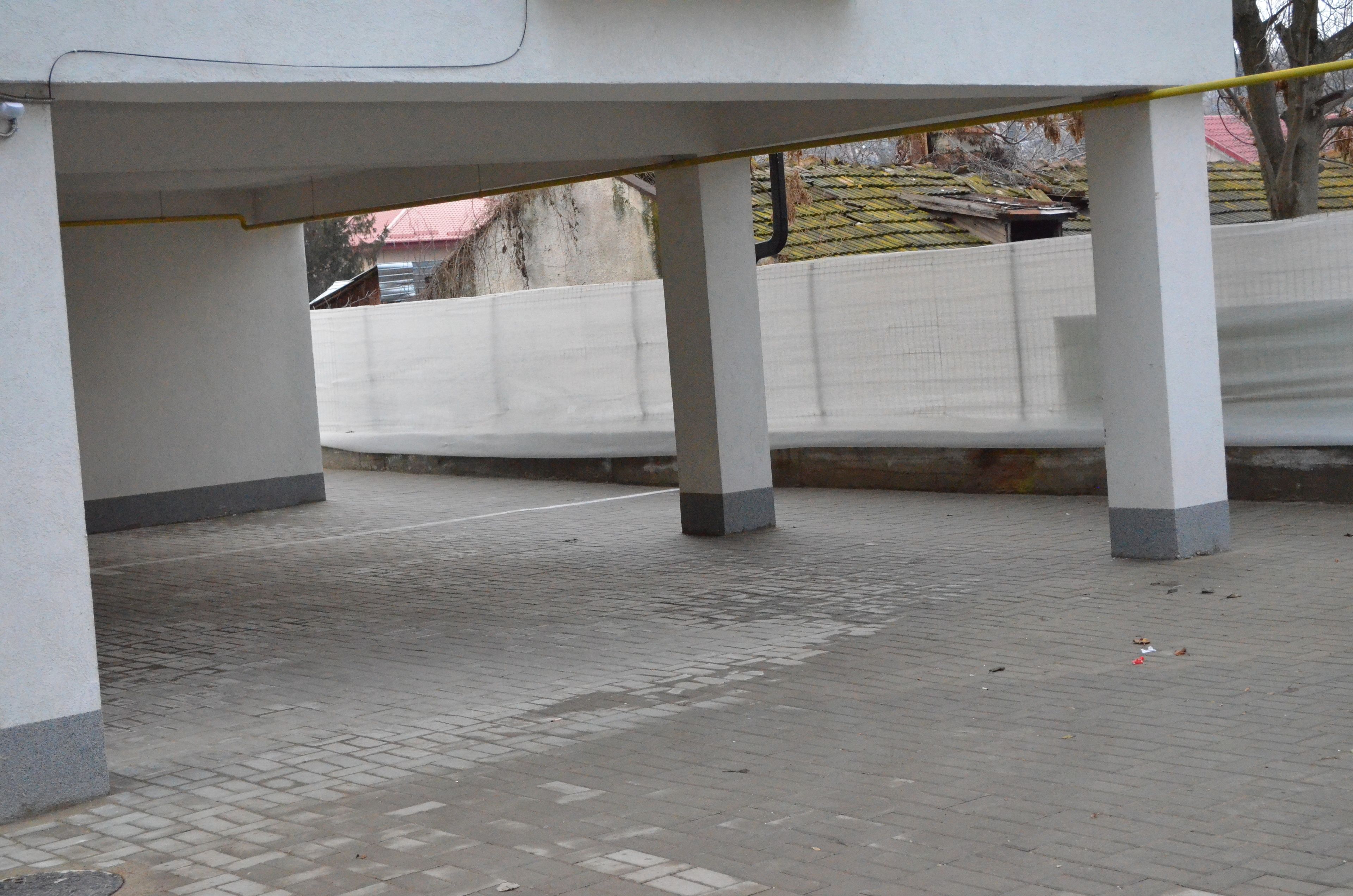An outdoor covered area with tiled flooring and concrete pillars.