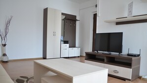 A modern living room with a sofa, a coffee table, a TV stand with a flat-screen TV, a cabinet, and a decorative vase. - Alexys Residence 8 (Iasi)
