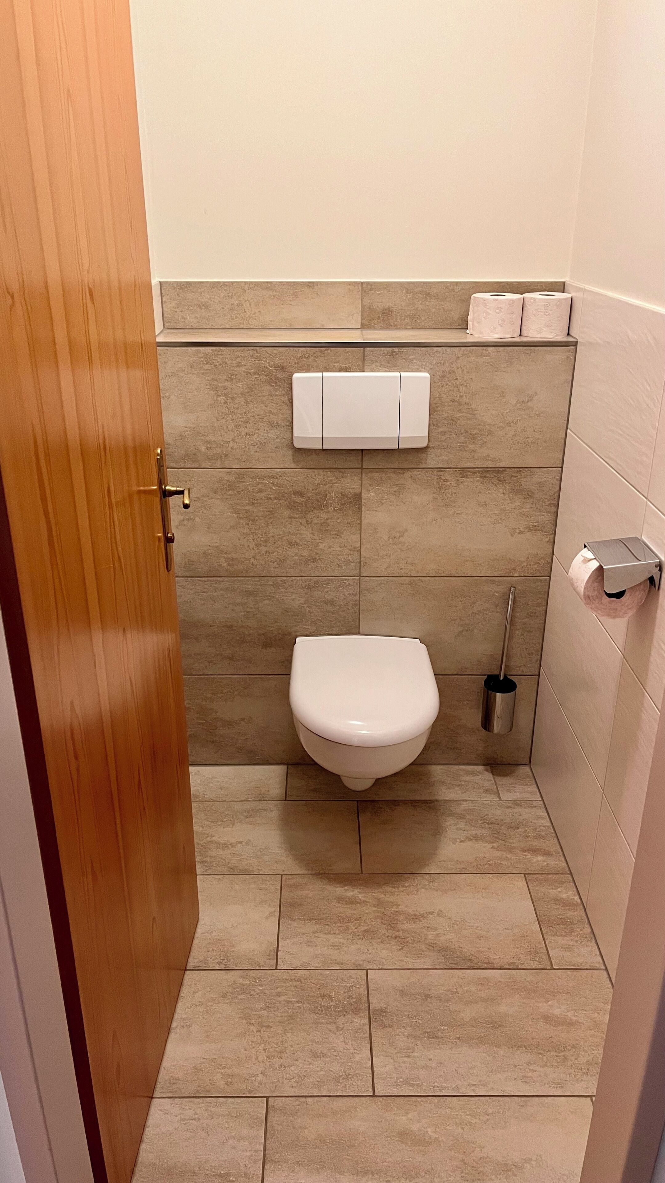 Un baño pequeño con un inodoro, un dispensador de papel higiénico y un secador de manos.