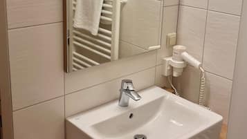 Un bagno con lavandino bianco, specchio e porta asciugamani.
