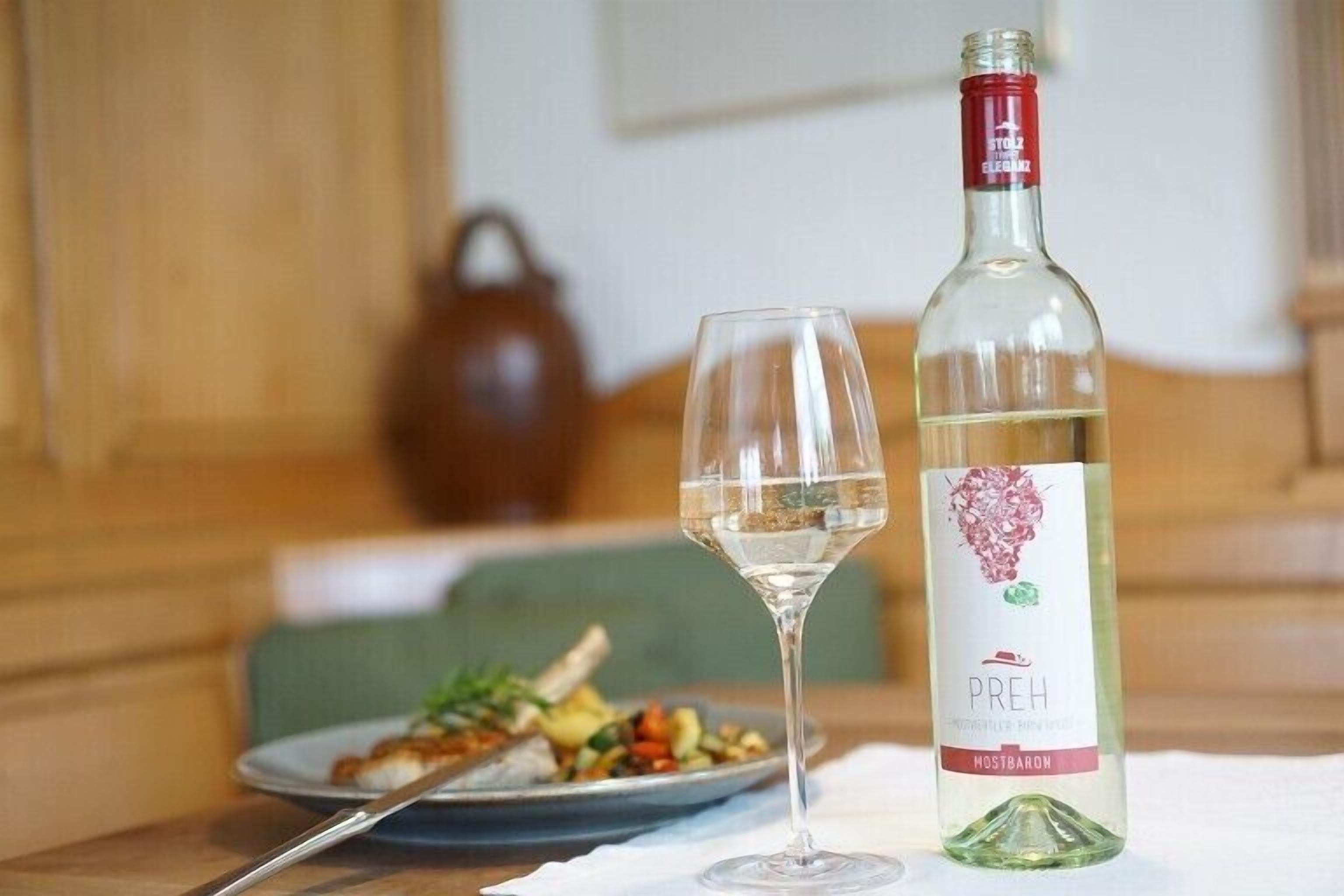 Una botella de vino blanco y una copa sobre una mesa con un plato de comida.