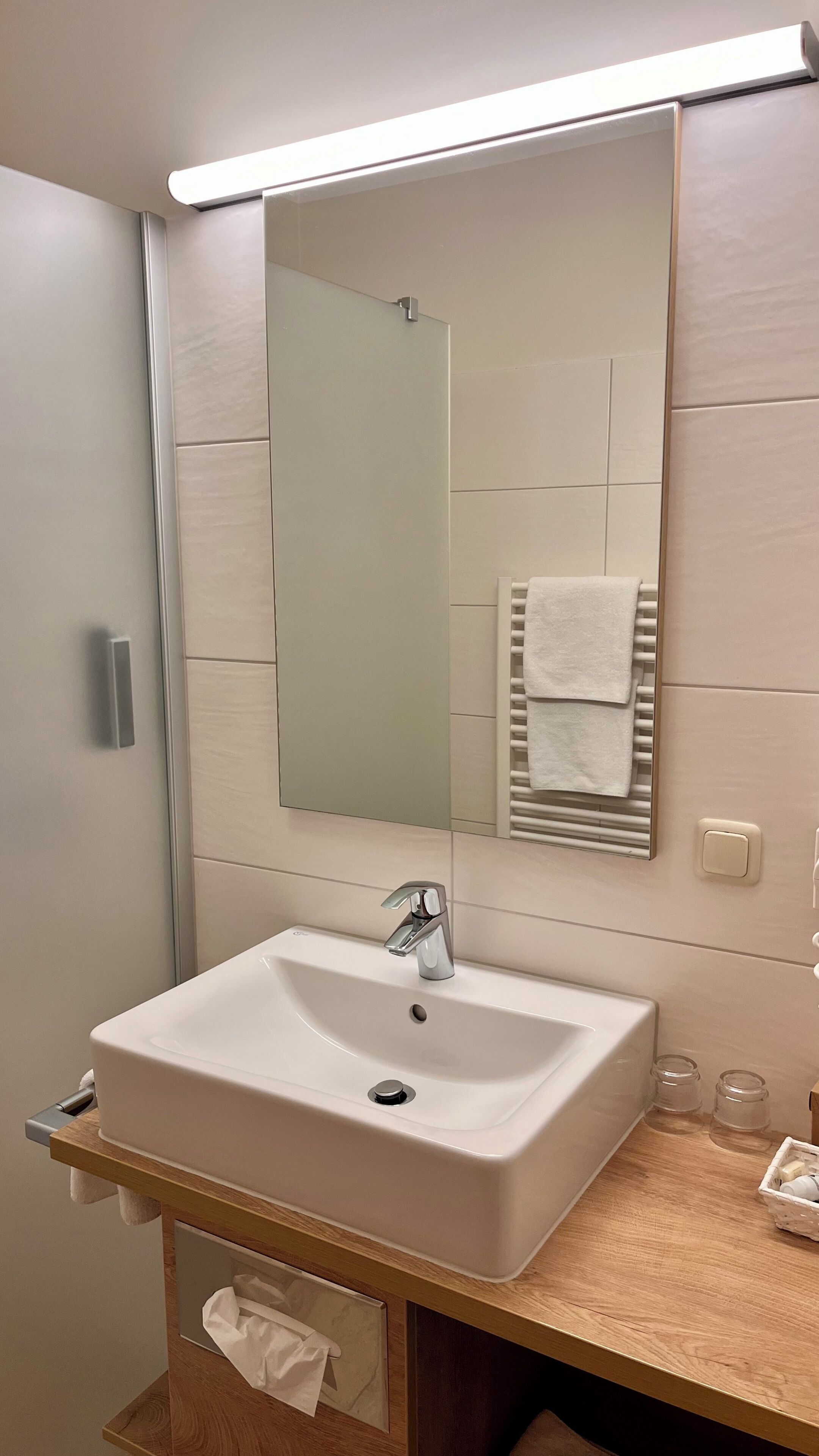 Ein Badezimmer mit einem weißen Waschbecken, einem Spiegel und einem Handtuchhalter.