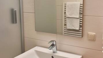 Ein Badezimmer mit einem weißen Waschbecken, einem Spiegel und einem Handtuchhalter.