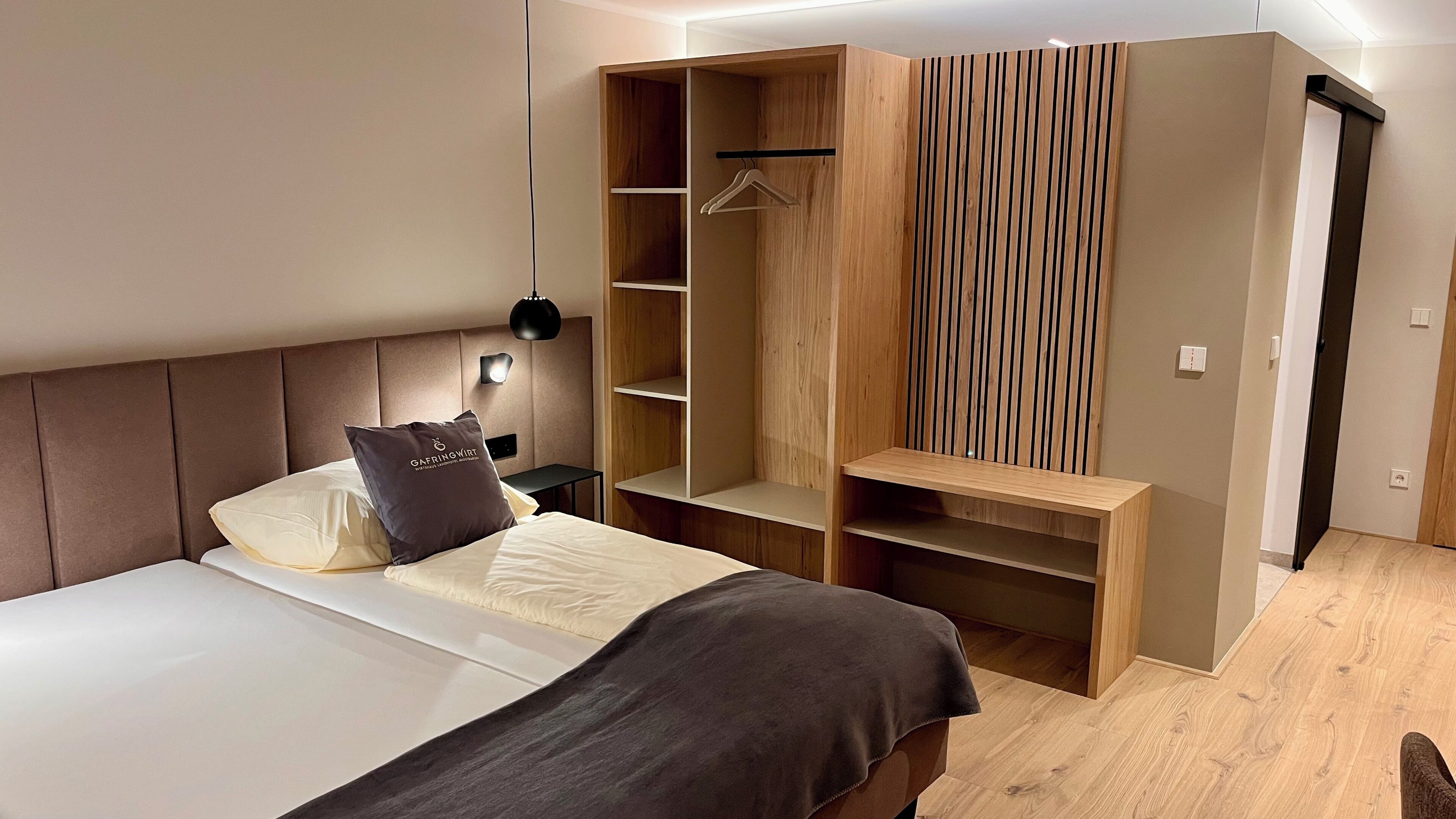A modern bedroom with a bed, a hanging wardrobe, and a bedside table.