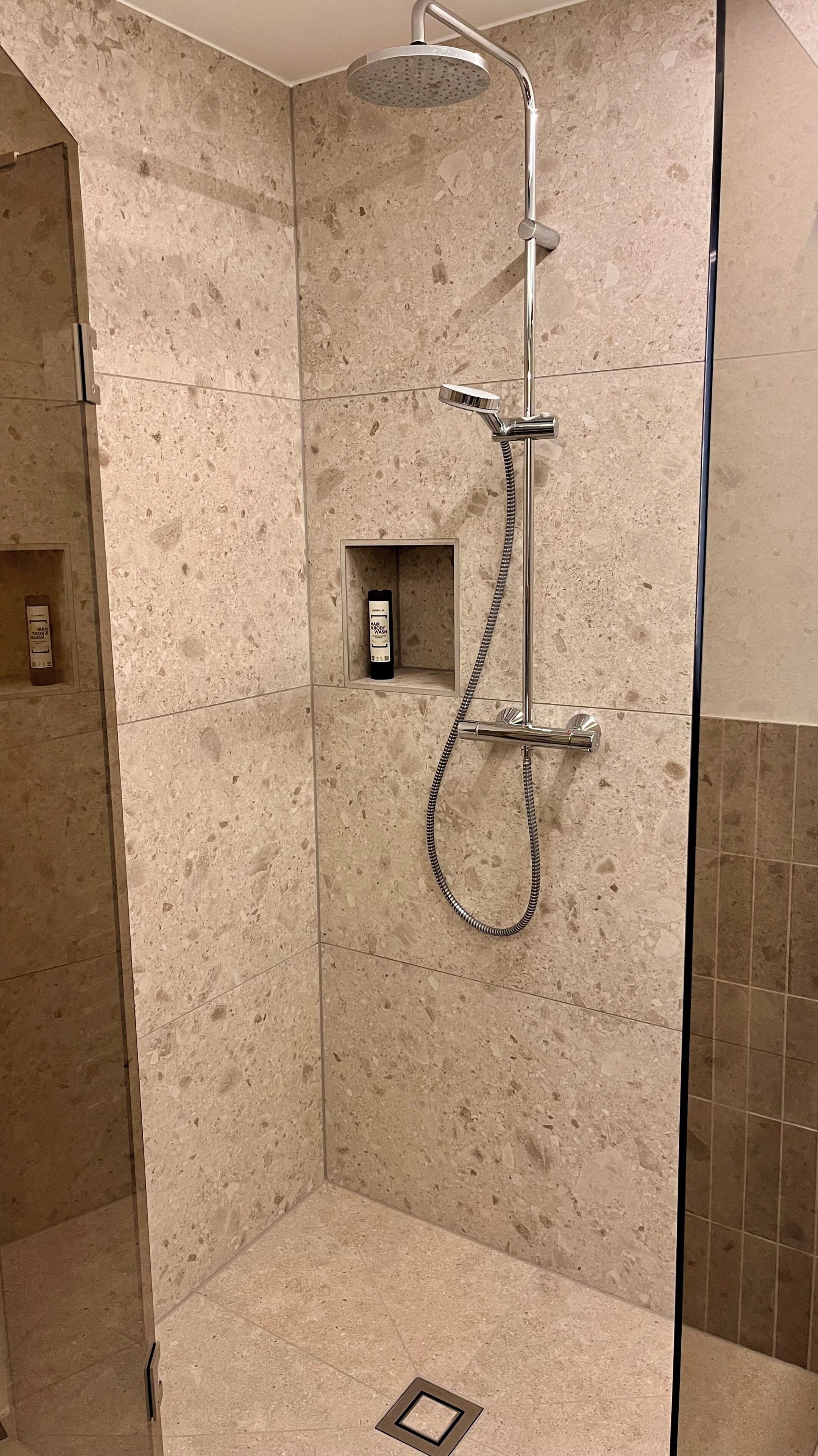 A shower with a handheld showerhead, a handheld showerhead, and a wall-mounted showerhead.