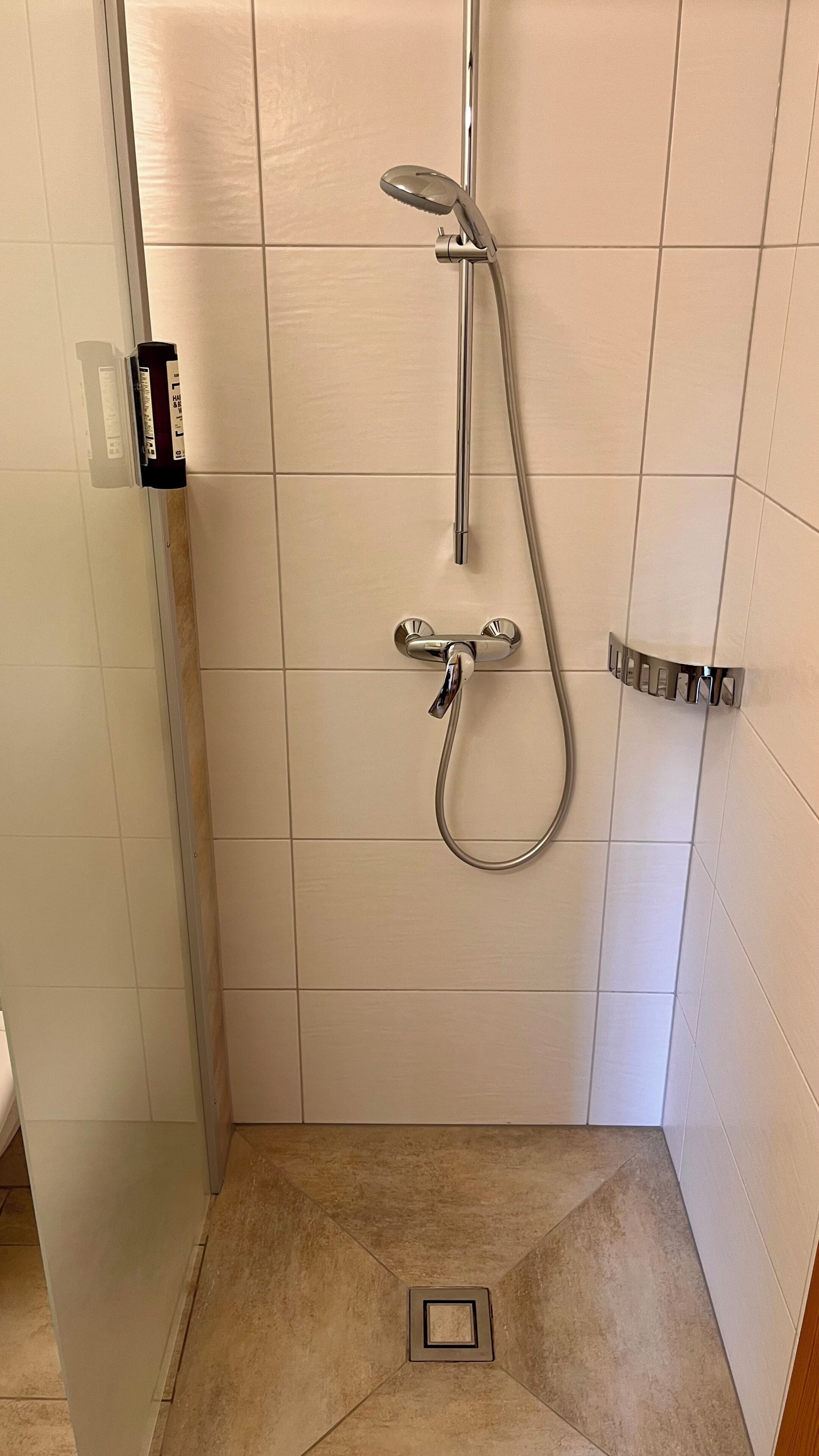 Een douche met een handdouche en een kraan op de muur.