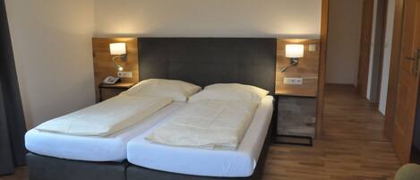 A double bed with a dark headboard, two bedside tables with lamps, and a wooden floor.