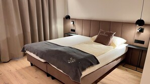 Una habitación de hotel moderna con una cama, cortinas y un cabecero.