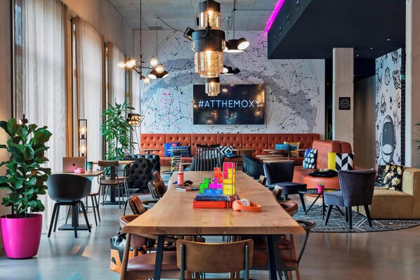A modern lounge area with a long wooden table, comfortable seating, and a large wall map.