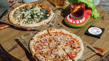 Dos pizzas sobre una tabla de madera, con un menú y una bebida en una mesa.