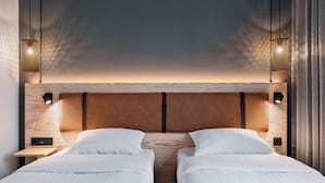 A double bed with a wooden headboard, two bedside tables, and wall-mounted lamps. - Moxy Darmstadt (Darmstadt)